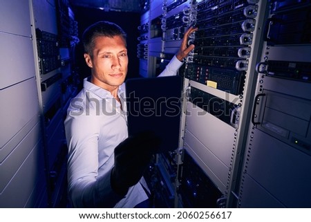 Serious engineer checking IT equipment in server room