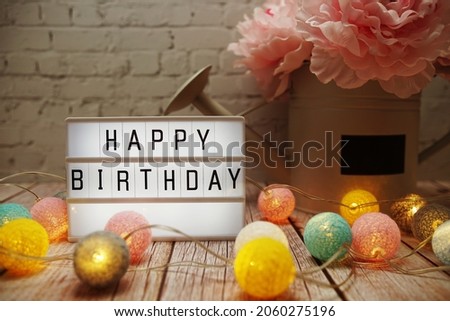 Happy Birthday text on lightbox on wooden background