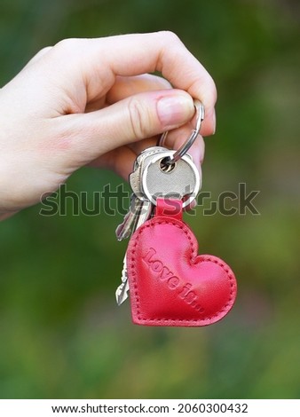 red leather key trinket heart shape closeup photo in human hands 