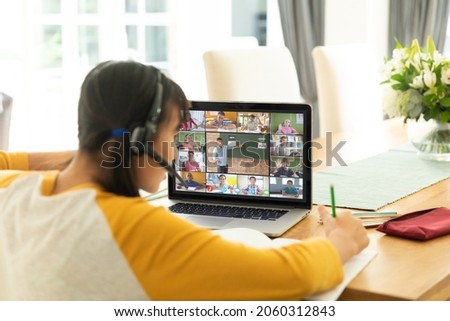 Asian girl using laptop for video call, with smiling diverse elementary school pupils on screen. communication technology and online education, digital composite image.