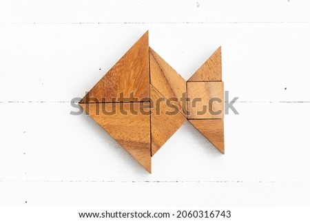 Wood tangram puzzle in fish shape on white wood background