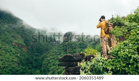 Traveler taking photo of mist in mountain at peak while hiking and camping, travel in nature.