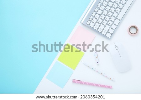 Computer keyboard with mouse and office supplies on colorful background