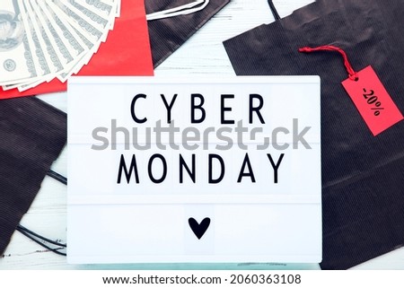 Lightbox with inscription Cyber Monday, shopping bags, and dollar banknotes on wooden background