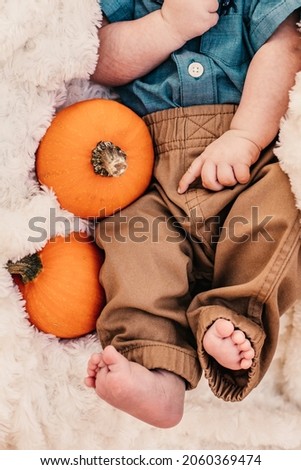 A newborn next to pumpkins for the month of October.