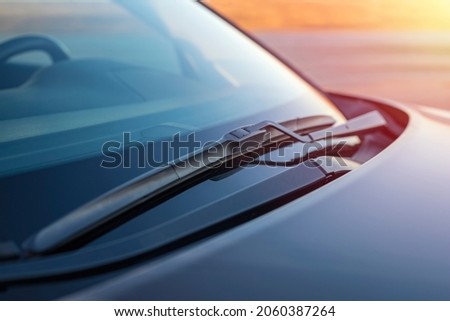 Brushes on the windshield of the car against the backdrop of soft rays of the sun, sunset. Concept for cleaning products, polishing, anti-rain Royalty-Free Stock Photo #2060387264