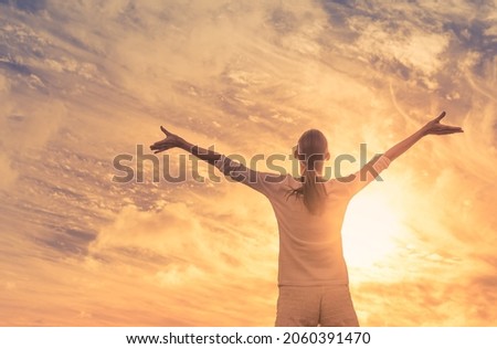 Happiness and bliss, young woman feeling grateful with arms up to the sunny sky. 