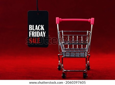 Black Friday. Sale label with supermarket trolley on dark red background. Selective focus.                                         