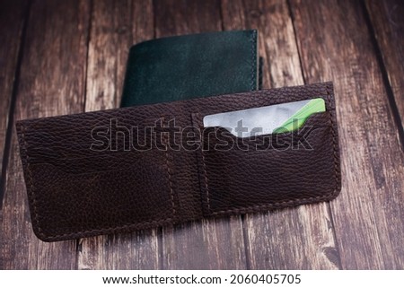 Wallet made of genuine brown leather on a wooden background, goods for men and women made of soft genuine light leather, accessories, top view, keychain,