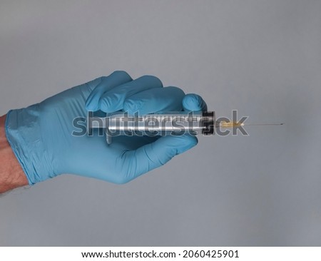 Syringe with needle in doctors hands in glove.