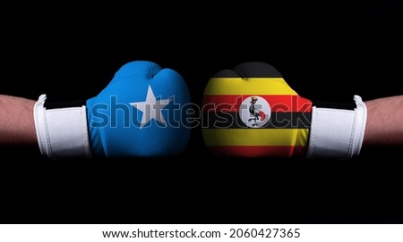 Two hands of wearing boxing gloves with Uganda and Somalia flag. Boxing competition concept. Confrontation between two countries