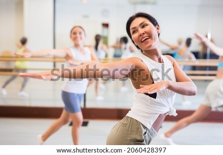  girl dancing modern dance in fitness studio with other dancers