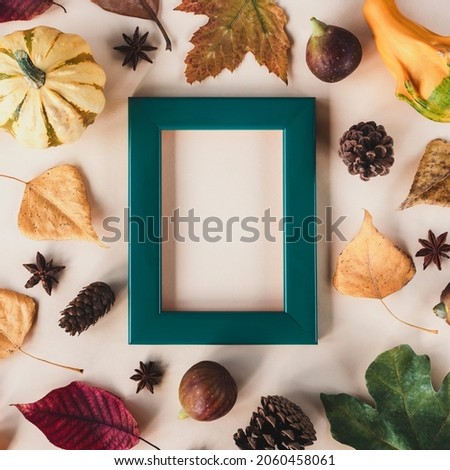 Blank picture frame and autumn leaves, pumpkins, figs and cones on light beige background. Mock up, top view, copy space