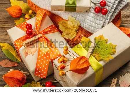 Zero waste gift concept with autumn design. Warm sweaters, fall leaves, thematic decor. Soft light, old wooden boards background, close up