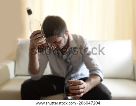  drunk business man at home lying asleep on couch sleeping wasted holding whiskey glass indoors in alcoholism problem , alcohol abuse and addiction concept looking messy and sick  Royalty-Free Stock Photo #206047204