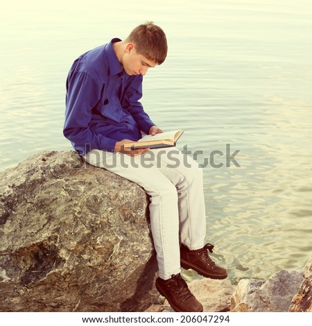 Toned photo of Teenager reading a Book near the Water