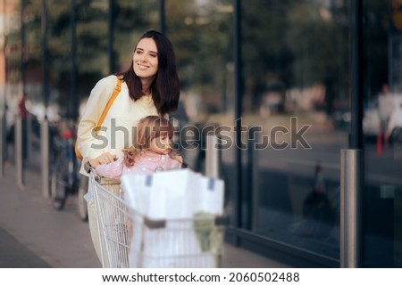 

Happy Woman Pushing a Supermarket Shopping Cart. Funny mom and child going to a shopping spree together
