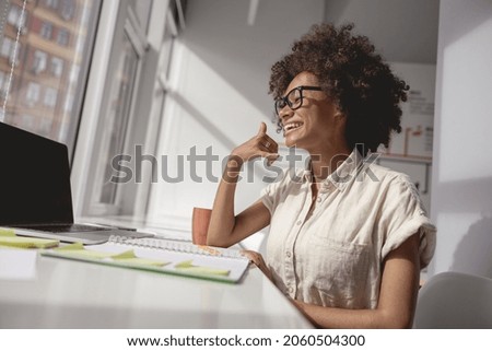 Happy woman communicating in sign language online at a laptop from office while sitting near window
