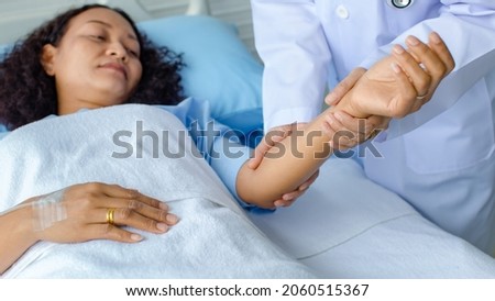 Doctor holds the hand of Asian female patient on bed in hospital and checkup nervous system for cure and treatment. Concept of Guillain barre syndrome and numb hands disease or vaccine side effect.