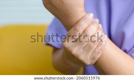 Woman using hand to hold other on arm with and feeling pain, suffer, hurt and tingling. Concept of Guillain barre syndrome and numb hands disease.