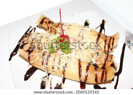 Fried bananas rolled with skin dough, sprinkled with cheese and covered with chocolate