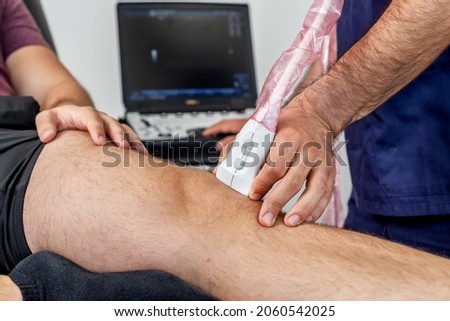 Close-up of a physiotherapist performing an ultrasound of the knee on a patient lying on the stretcher Royalty-Free Stock Photo #2060542025
