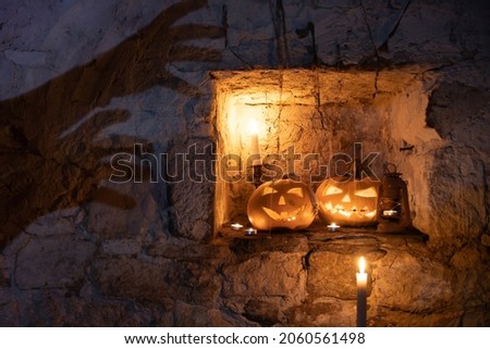 Jack O' Lantern glowing in old cellar, ghost silhouette on the wall.Creepy Halloween background