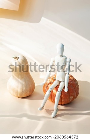 Pumpkins with wooden mannequin creative still life. Minimal fall season holiday concept.