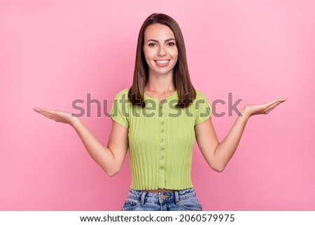 Photo of cute brunette young lady hold empty space wear green t-shirt isolated on pink color background