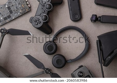 Overhead flat lay of black technology devices and gadgets on a grey background