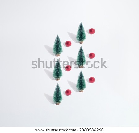 Arranged green New Year and Christmas tree with red bauble on a white pastel background. Pattern. Copy space. Minimal design and concept.