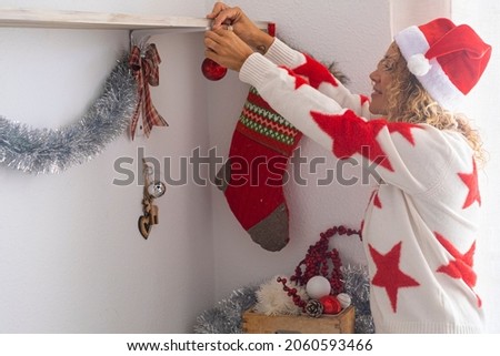 Happy adult woman decorating home with christmas socks and balls - holidays winter december season. new year eve and christmas celebration people