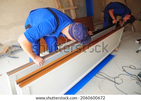 Contractors Installing, Repair, Garage Door. Contractors installing garage door weatherproofing garage door seal.  Royalty-Free Stock Photo #2060600672