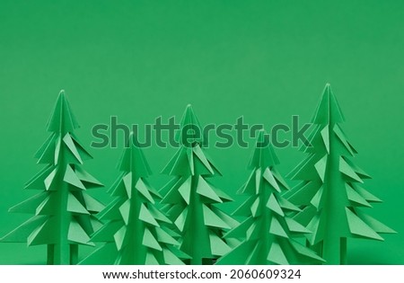 Christmas trees paper artwork in green background. Christmas tree paper cutting design card. DIY 3d made of paper. handmade 3d pine tree. New Year background with paper tree