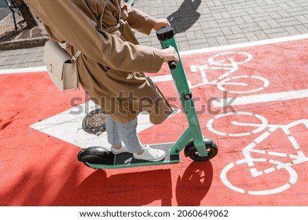 traffic, city transport and people concept - close up of woman riding electric scooter along red bike lane with signs of bicycles on street
