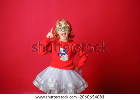 little girl on a red background in carnival christmas glasses 