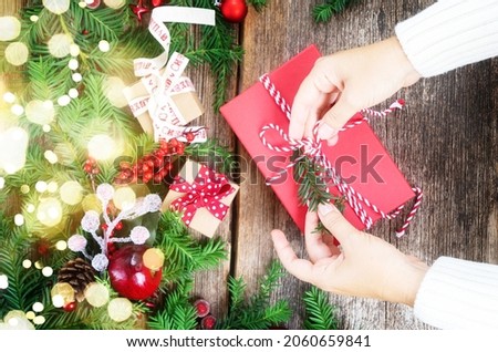 Christmas gift giving and zero waste concept - someones hands wrapped christmas gift box, border on wooden background