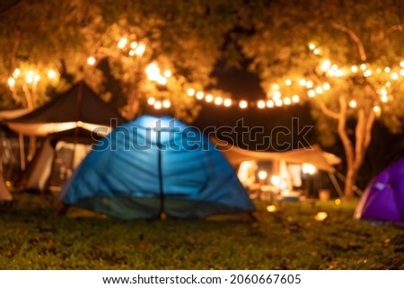Blurred photo of camping tents with lighting decoration at night.