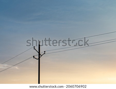 Electricity pole over blue and orange sky minimal photo.