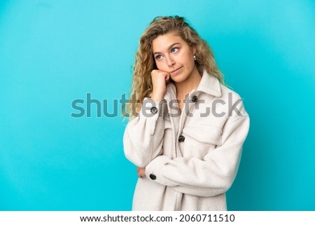 Young blonde woman isolated on blue background with tired and bored expression