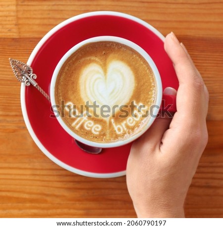 Coffee Break. Woman with cup of cappuccino at  wooden table, top view