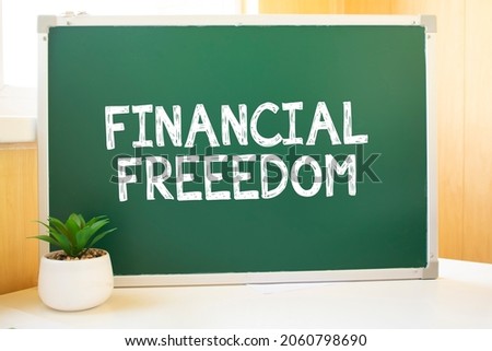 FINANCIAL FREEEDOM in chalk on the school board, Search engine optimization and websites. Desk, swept balls of paper, computer keyboard