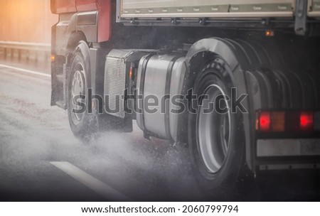 Truck chassis and wheels on a wet road in rainy weather, close-up. Safety concept and tire grip on wet roads, braking distances under emergency braking, close-up Royalty-Free Stock Photo #2060799794
