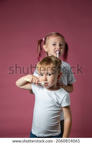 Smiling caucasian little boy and girl cleaning his teeth with electric sonic and manual toothbrush on pink background.