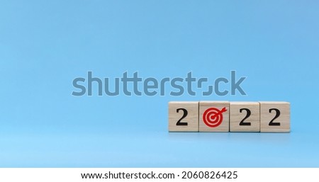 New year goal. number and dart board icon written on wooden cube block stack on blue background, change from 2021 to 2022, new year congratulation, countdown to 2022, goal and target plan concept
