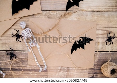 A kraft paper envelope and felt bats, skeletons, spiders around on a wooden background. Halloween decor. Handmade holiday decorations.