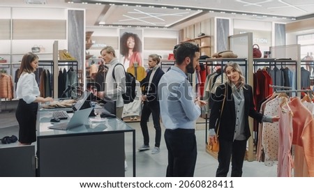 Clothing Store: Diverse Group of Costumers Shopping, bying Clothes and Merchandise at Checkout Cashier Counter. Retail Shopping Mall Assistant Helps Clients, Selling Stylish Designer Brands.