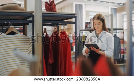 Clothing Store: Female Visual Merchandising Professional Uses Tablet Computer To Create Stylish Collection. Fashionable Shop Sales Retail Assistant Checks Stock. Small Business Owner Orders Items Royalty-Free Stock Photo #2060828504