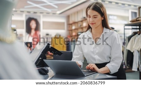 Clothing Store: Businesswoman and Visual Merchandising Specialist Uses Laptop To Create Stylish Collection. Fashion Shop Sales Retail Manager Checks Stock. Small Business Owner and Designer Works
