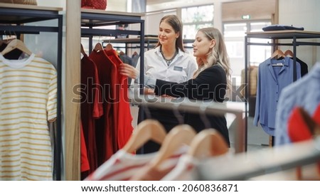 Clothing Store: Professional Sales Associate Talks with Beautiful Female Customer, Shopping for Stylish Clothes, Choosing Trendy and Sustainable Brands. Stylish Fashionable Shop in Shopping Mall